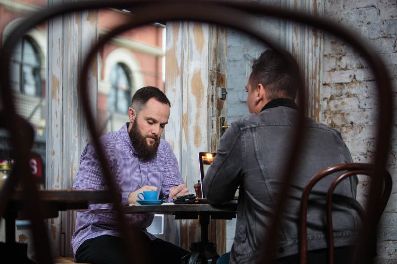 commercial photography of two men having business meeting with coffee and laptop in melbourne