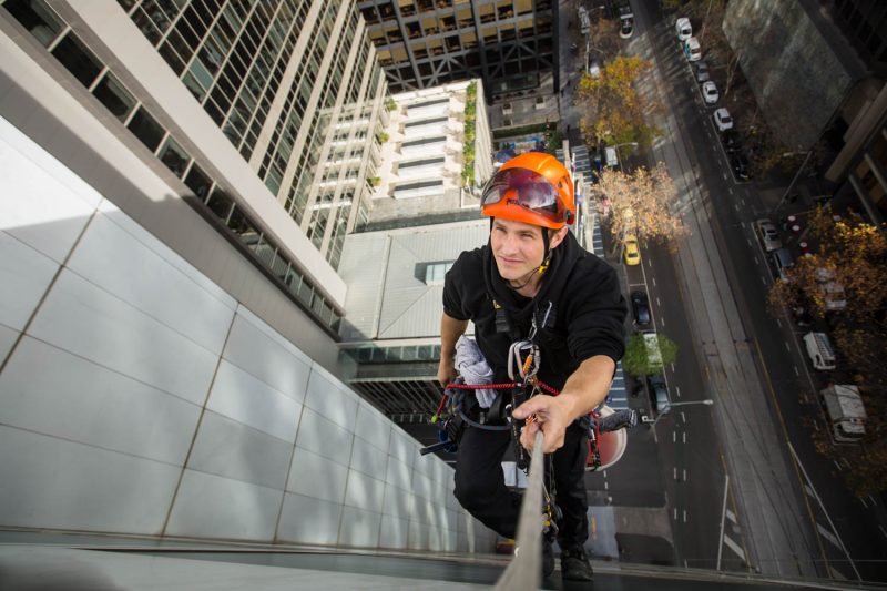 melbourne commercial window washer hanging over edge of building